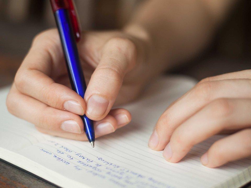 Человек пишет в тетрадь